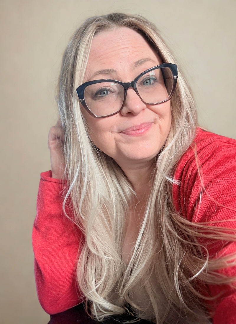 Gina Dunn, founder brand strategist in Almere Netherlands, smiling with long blonde hair, glasses, and a red top